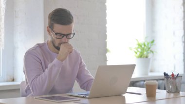 Genç Yetişkin Adam dizüstü bilgisayar kullanırken öksürüyor