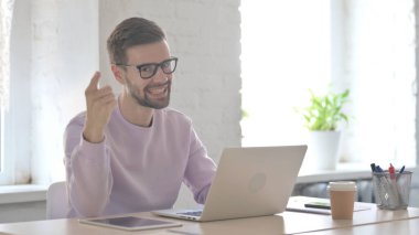 Genç Yetişkin Adam Dizüstü bilgisayar kullanırken Kamerayı Gösteriyor