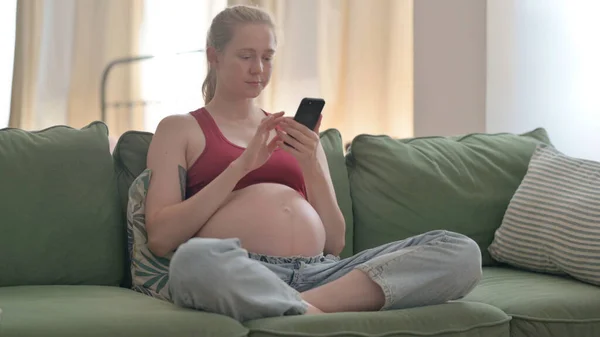 Pregnant Woman Using Smartphone While Sitting Sofa — Photo