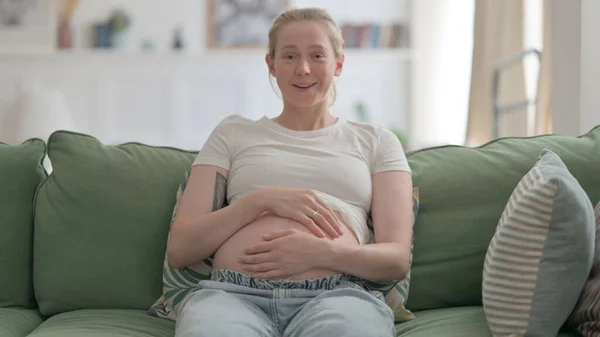 妊娠中の女がソファに座っている間にビデオチャットで話す — ストック写真