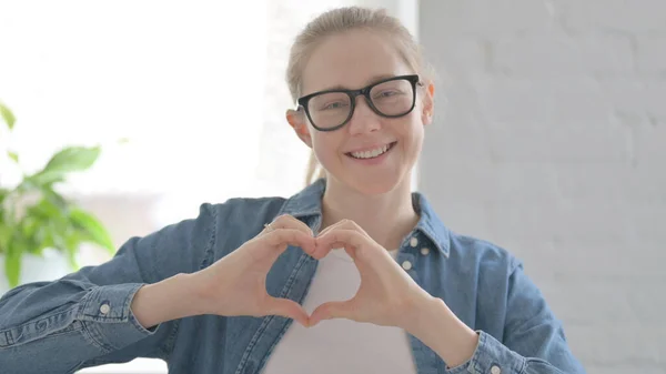 Loving Beautiful Woman showing Heart Shape by Hands Indoor