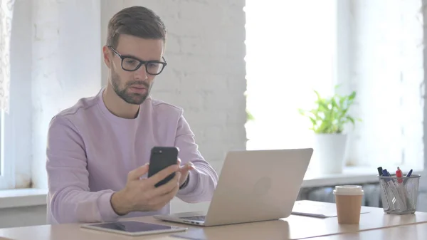Young Adult Man Using Smartphone While Using Laptop — Stock Photo, Image