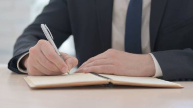 The Close Up of Young Businessman Writing on Notebook
