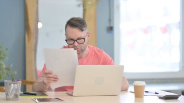 Young Adult Man Working on Laptop and Documents