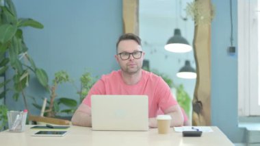 Creative Adult Man Looking at Camera while using Laptop