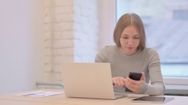 Creative Young Woman using Phone and Laptop for Work