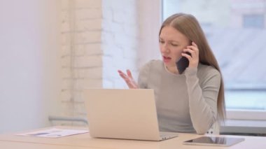 Angry Creative Young Woman Talking on Phone at Work