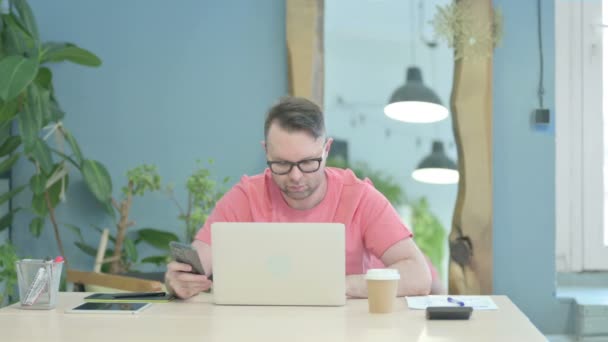 Creative Adult Man Using Smartphone While Using Laptop — Stockvideo