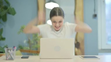 Young Woman Celebrating Online Success on Laptop