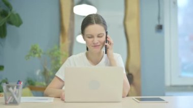 Young Woman Talking on Phone to Discuss Work
