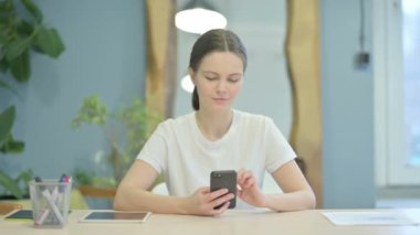 Young Woman Browsing Internet on Smartphone at Work