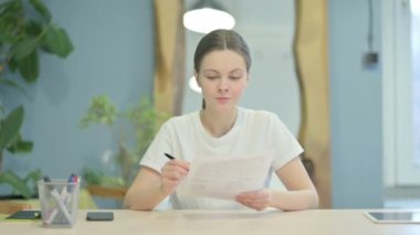Young Woman Celebrating while Reading Documents at Work