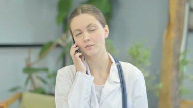 Portrait of Young Female Doctor Talking on Phone in Clinic