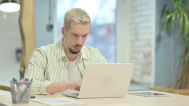 Dizüstü Çalışan Baş ağrısı ile Stresli Genç Adam