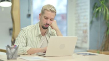 Uyuyan genç adam işte oturuyor.