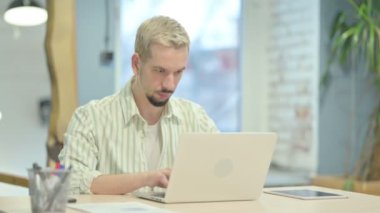 Dizüstü bilgisayar kullanırken Kameraya Bakan Ciddi Genç Adam