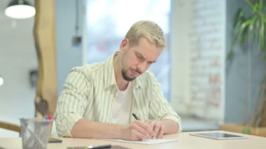 Hüsrana uğramış genç adam mektup yazmaya çalışıyor.