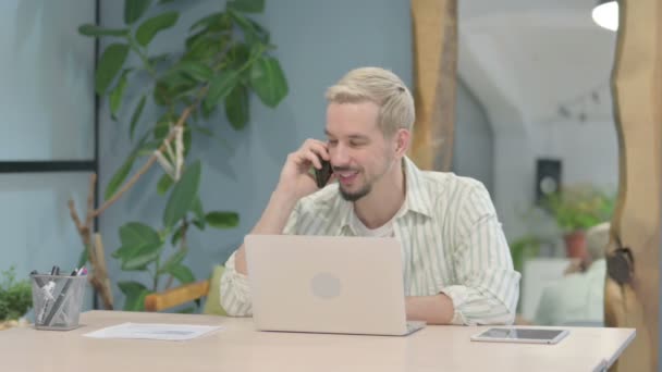 Modern Ung Man Talar Telefon När Använder Laptop — Stockvideo