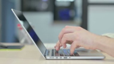 Dizüstü bilgisayarda yazan adamın yan görünümü