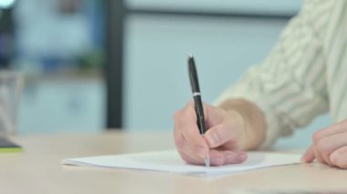 Close up of Young Man Writing in Office