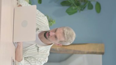 Dizüstü bilgisayarda yazan sıradan genç adamın dikey videosu
