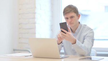Genç İşadamı dizüstü bilgisayar kullanırken Smartphone kullanıyor