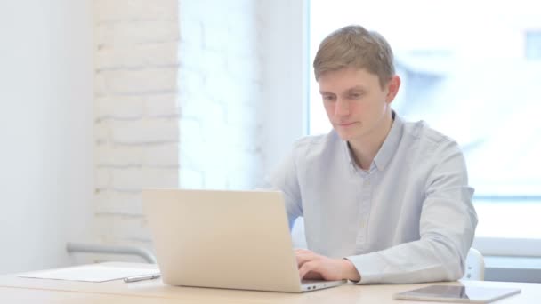 Junger Geschäftsmann Schüttelt Zustimmend Den Kopf Während Laptop Arbeitet — Stockvideo