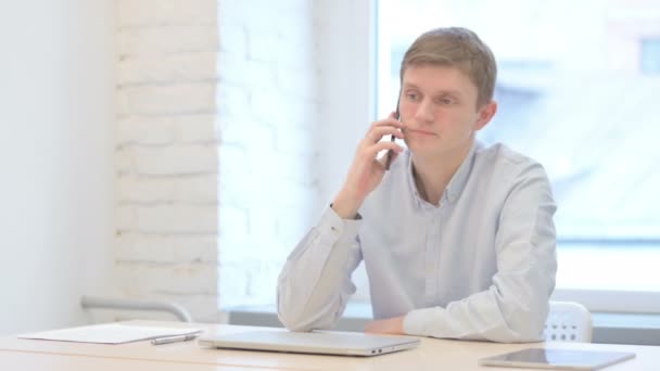 Νεαρός Επιχειρηματίας Μιλώντας Στο Τηλέφωνο Στο Γραφείο — Αρχείο Βίντεο