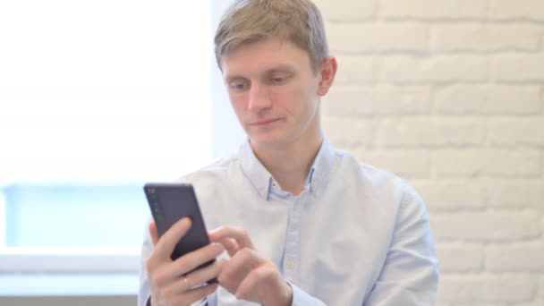 若いビジネスマンがスマートフォンで勝利を祝う — ストック動画