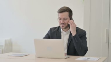 dizüstü bilgisayar kullanırken telefonda konuşurken işadamı