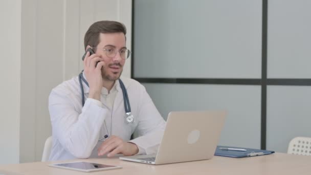 医生在使用笔记本电脑时谈电话 — 图库视频影像