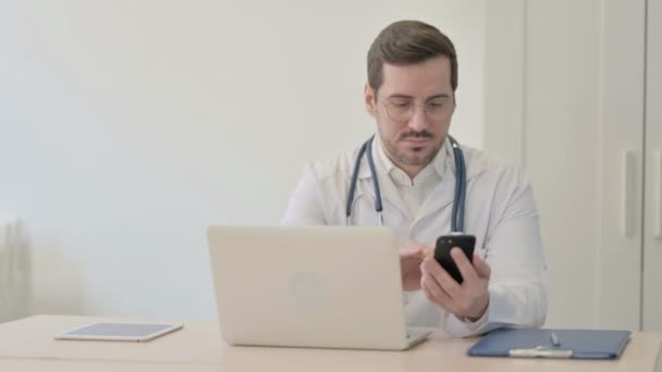 Doktor Používající Smartphone Během Používání Notebooku — Stock video