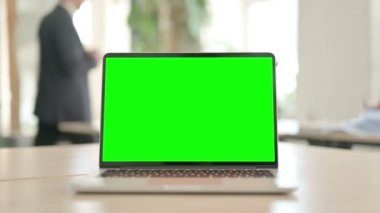 Laptop with Green Screen on Desk in Office