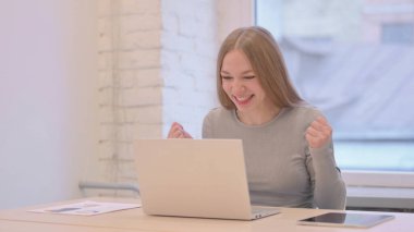 Creative Young Woman Celebrating Online Success on Laptop