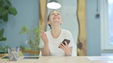 Successful Young Woman Celebrating Win on Smartphone