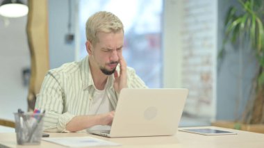 Genç adam işte diş ağrısı çekiyor.