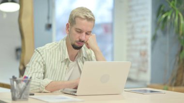 Uyuyan genç adam işte oturuyor.