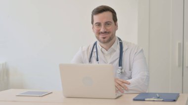 Doktor Laptop kullanırken kameraya gülümsüyor