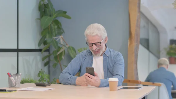 Senior Old Man Browsing Internet on Smartphone at Work