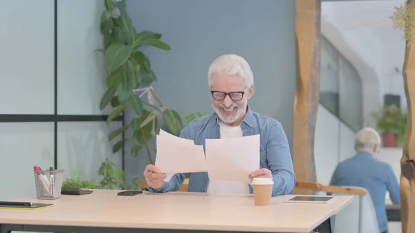 Senior Old Man Reading Documents at Work, Paperwork