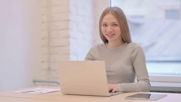 Creative Young Woman Smiling Camera While Using Laptop — 图库照片