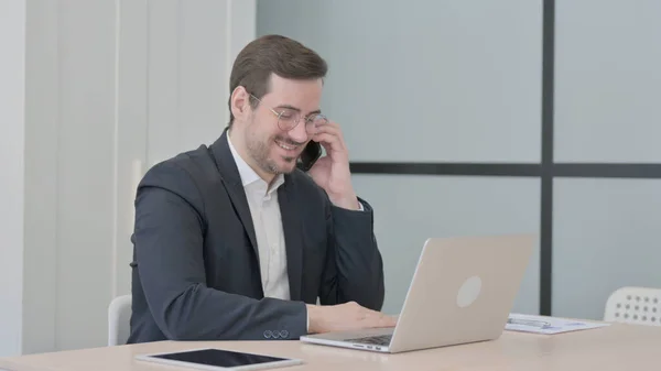 Affärsman Som Pratar Telefonen Medan Använder Laptop — Stockfoto