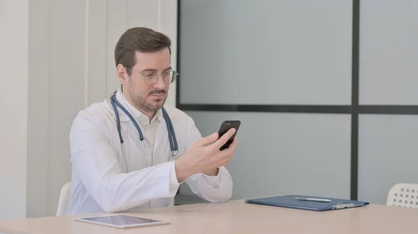 Lekarz Przeglądanie Smartfona Klinice — Zdjęcie stockowe