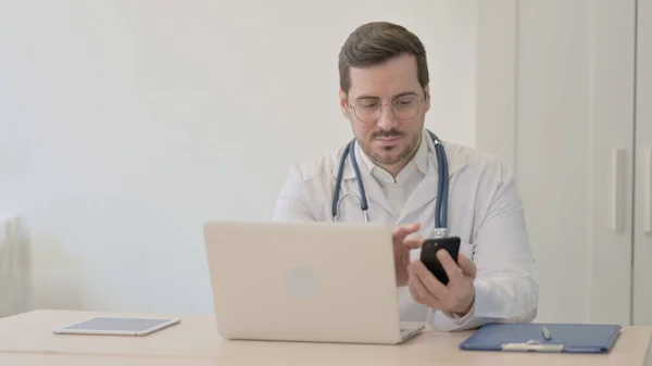 Doctor Usando Smartphone Mientras Usa Laptop —  Fotos de Stock