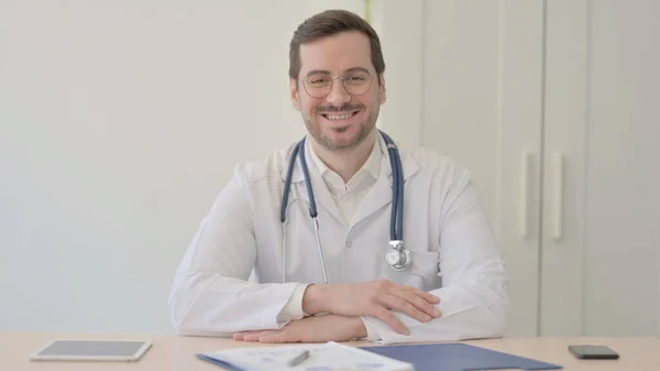 Doktor Klinikte Otururken Kameraya Gülümsüyor — Stok fotoğraf