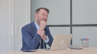 Dizüstü bilgisayarda çalışan bilek ağrısı olan bir iş adamı