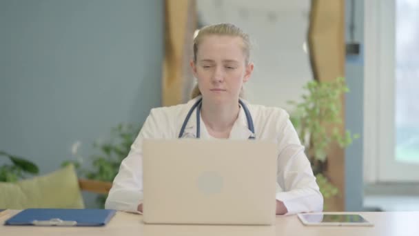 在笔记本电脑上工作的女医生朝著照相机看 — 图库视频影像