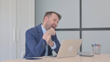 Dizüstü bilgisayarda çalışan bilek ağrısı olan bir iş adamı