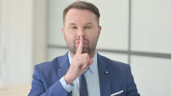 Portrait of Businessman with Finger on Lips