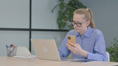 Laptop 'ta Çalışan ve Akıllı Telefon Kullanan Genç Kadın